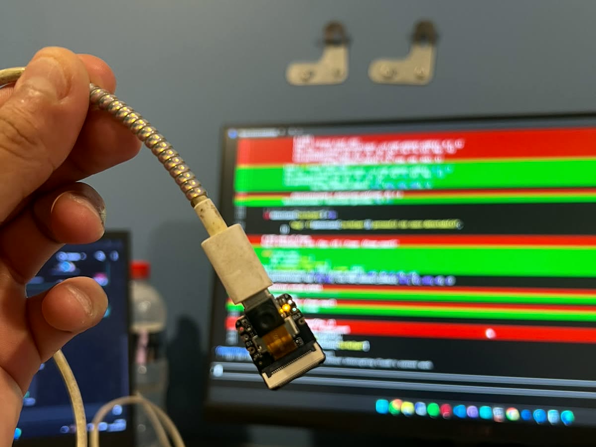La cámara embebida sostenida en la mano, con el registro del sistema corriendo detrás en el monitor
